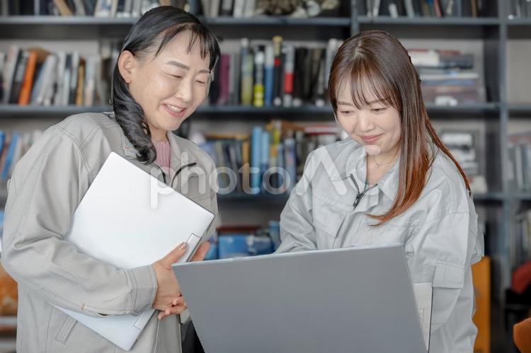 笑顔でPCを触る女性 作業服,女性,笑顔の写真素材