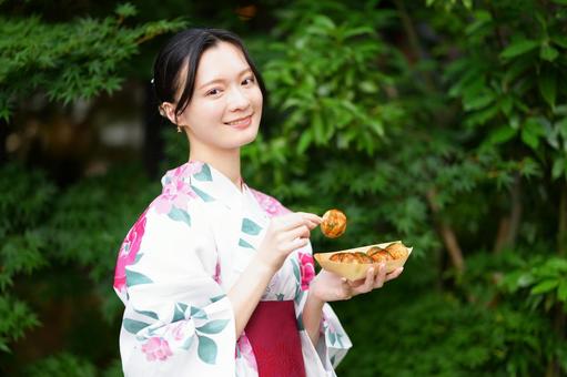 浴衣姿の女性が屋外でたこ焼きを持つ 女性,浴衣,たこ焼きの写真素材