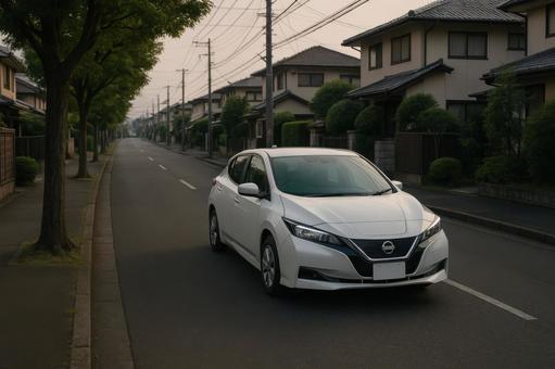 夕方の住宅街を走行する電気自動車(白) 夕方の住宅街を走行する電気自動車(白)の写真
