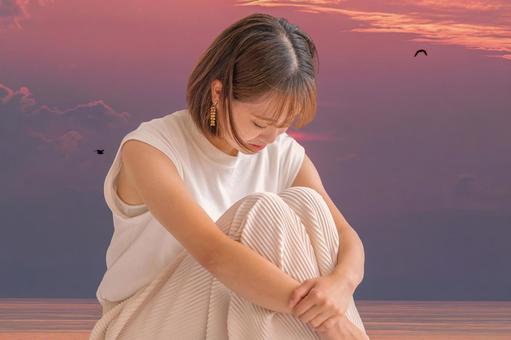 夕暮れの海と落ち込む女性 夕暮れの海と落ち込む女性 失望,失恋,挫折の写真素材