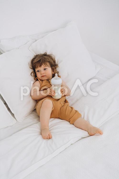 哺乳瓶を両手で持ち眠そうな子供 赤ちゃん,哺乳瓶,ミルクの写真素材