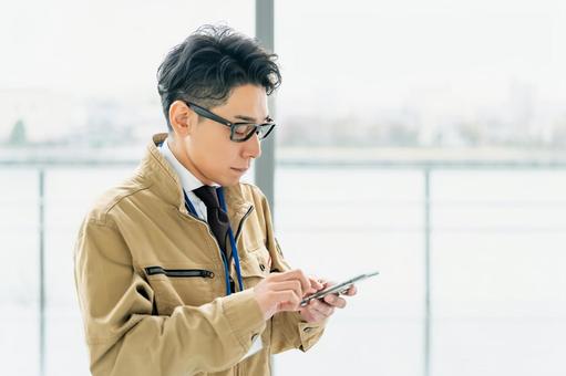 携帯電話を確認する作業服の男性 携帯電話を確認する作業服の男性 ビジネス,ビジネスマン,作業員の写真素材
