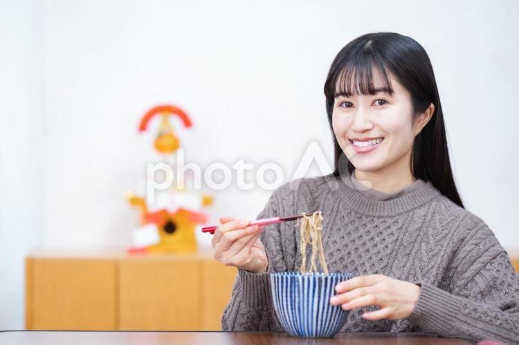 カメラ目線で年越しそばを持ち上げる女性 女性,持ちあげる,カメラ目線の写真素材
