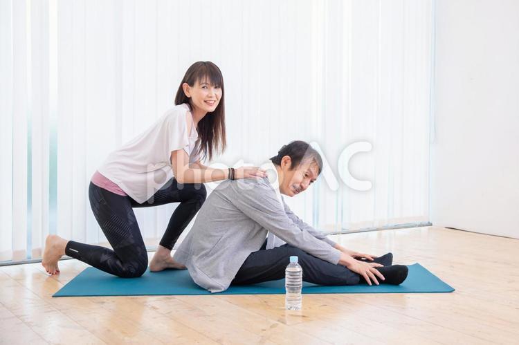 パーソナルトレーニングを受ける中高年男性 ストレッチ,前屈,柔軟体操の写真素材