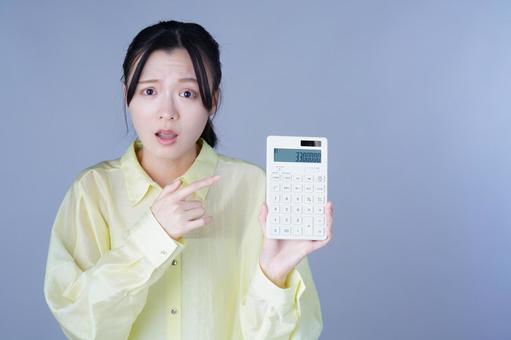 電卓を見せる黄色い服の女性の写真