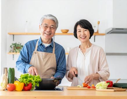 キッチンで会話しながら料理するシニア夫婦 キッチンで会話しながら料理するシニア夫婦の写真