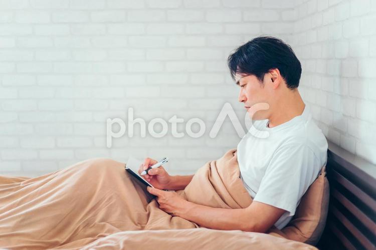 寝る前に勉強する男性 日記,勉強,書くの写真素材