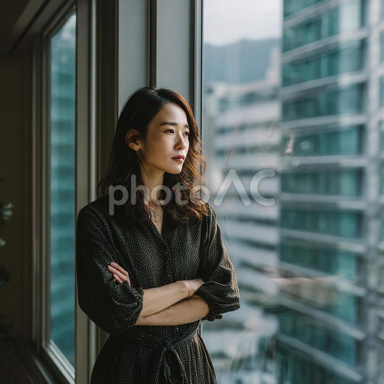 オフィス窓越しの静かな時間 日本人,女性,30代の写真素材