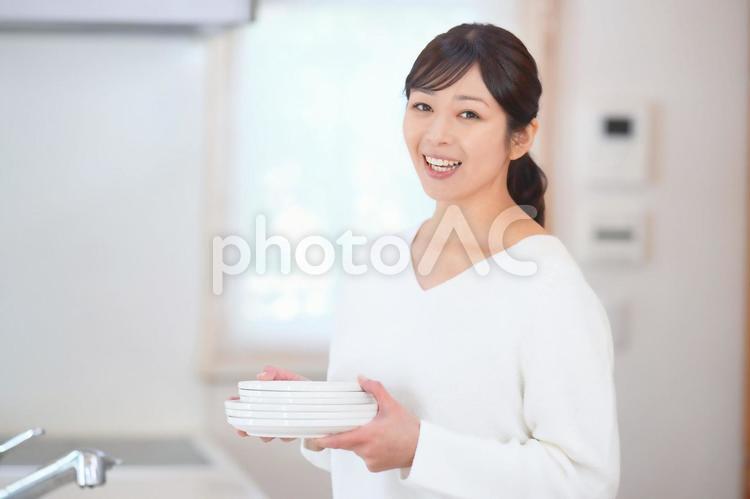 キッチンでカメラ目線で皿を持つ女性 女性,主婦,皿の写真素材