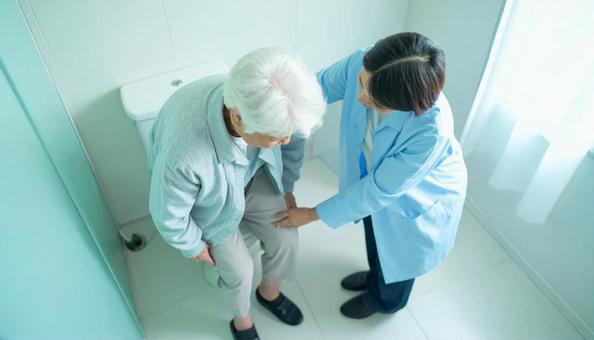 高齢女性のトイレの介助をしている家族 高齢女性のトイレの介助をしている家族の写真