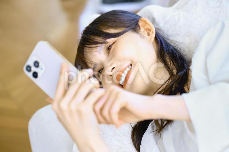 寝転んでスマホを見る女性　主婦　ソファ スマホ,女性,主婦の写真素材