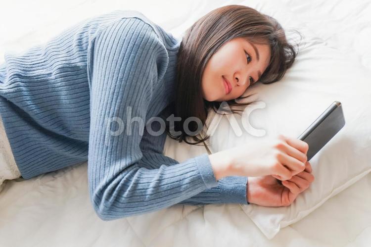 ベッドで寝る前にスマホを使う若い女性 休み,モバイル,マンガの写真素材