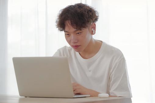 リビングでパソコン作業をする若い男性 リビングでパソコン作業をする若い男性 考える,悩む,真剣の写真素材