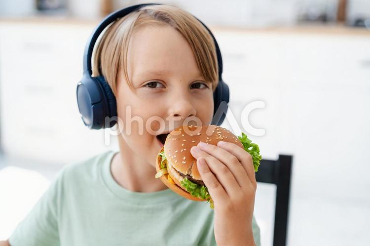 ハンバーアガーを持ってカメラ目線の男の子 男の子,人物,食事の写真素材