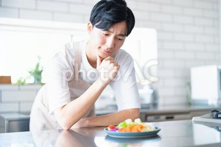 キッチンでエプロンをつけた若い男性　 男性,料理,クッキングの写真素材