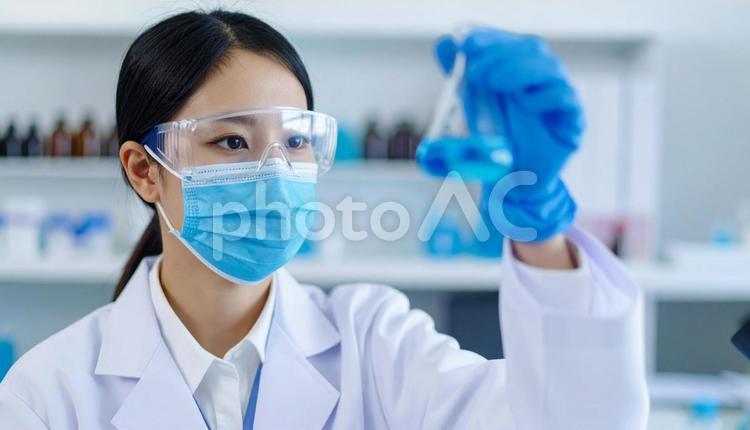 研究所で実験をする女性の研究者 試薬,フラスコ,マスクの写真素材
