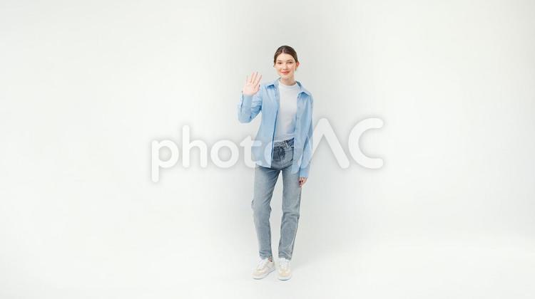 カメラ目線で右手で手を振る外国人女性 女性,笑顔,手を振るの写真素材