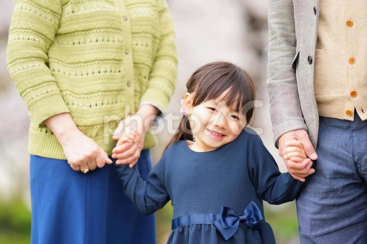 おじいちゃんおばあちゃんと手を繋いでいる女の子 女の子,小学生,子どもの写真素材