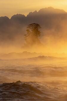 波打つ海と毛嵐に浮かぶ女岩_縦 毛嵐,日の出,朝日の写真素材