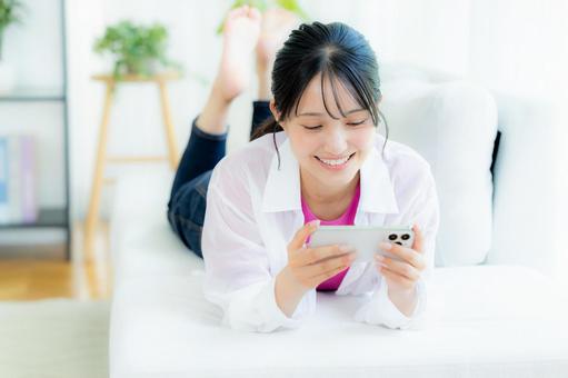 部屋でスマホを操作する若い女性 部屋でスマホを操作する若い女性 スマホ,若い女性,笑顔の写真素材