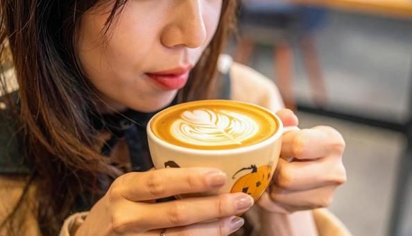 ハロウィンの飾り付けのカフェを楽しむ女性 ハロウィンの飾り付けのカフェを楽しむ女性の写真