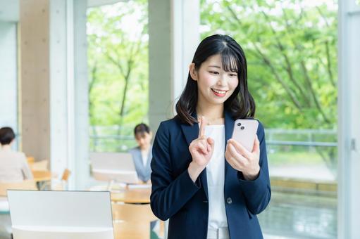 オフィスでスマホを使うビジネスウーマン オフィスでスマホを使うビジネスウーマンの写真