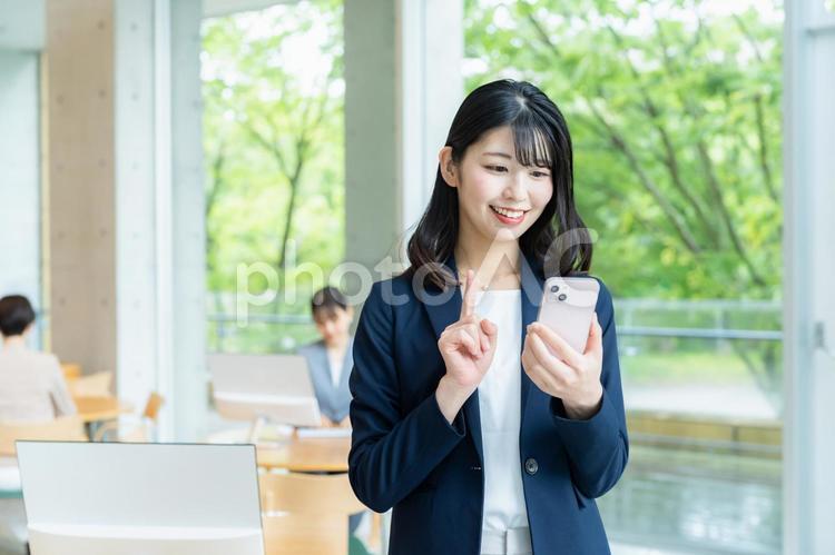 オフィスでスマホを使うビジネスウーマン ビジネスウーマン,スマホ,笑顔の写真素材
