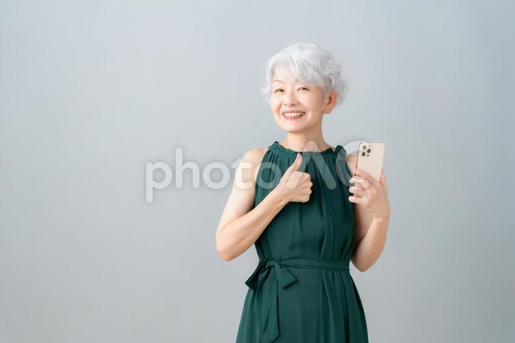 グレーバックでスマホを見るシニア女性 女性,スマホ,シニアの写真素材