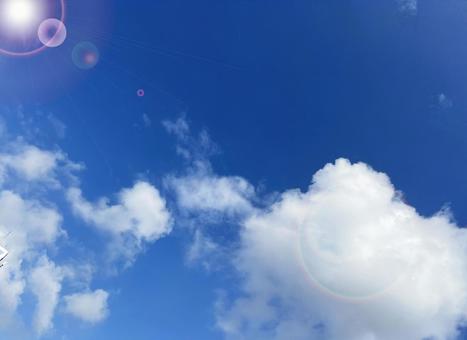 白いもくもく雲と青空と太陽の光の写真