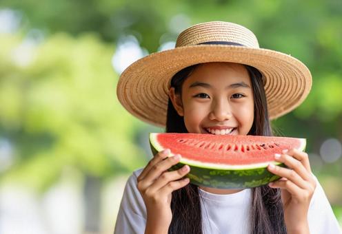 麦わら帽子の女の子がスイカを食べようと 麦わら帽子の女の子がスイカを食べようとの写真