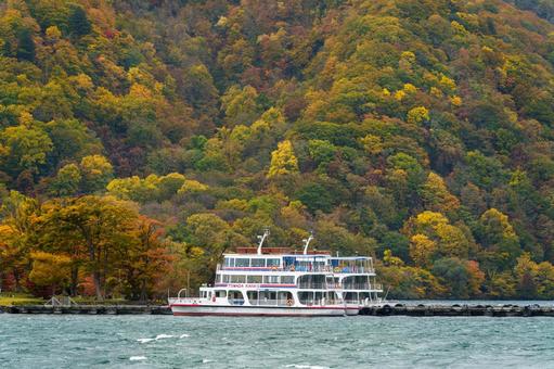 紅葉の十和田湖と遊覧船の写真