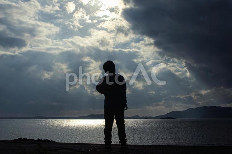 ＜五島の風景＞大浜で空を見詰める少年 子供,悩む,海の写真素材