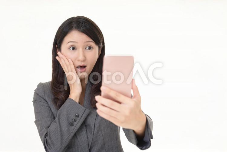 スマホの画面を見て驚く女性 女性,ビジネスウーマン,スマートフォンの写真素材