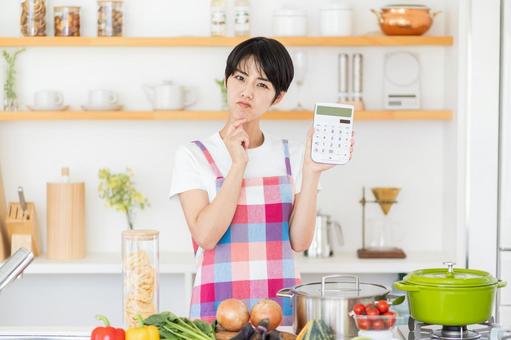 電卓を持って悩む主婦。 電卓を持って悩む主婦。の写真
