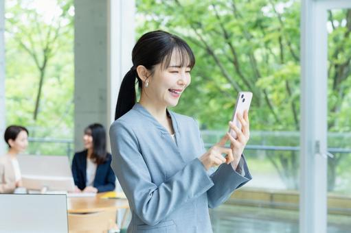 スマホを操作するビジネスウーマン スマホ,笑顔,ビジネスウーマンの写真素材