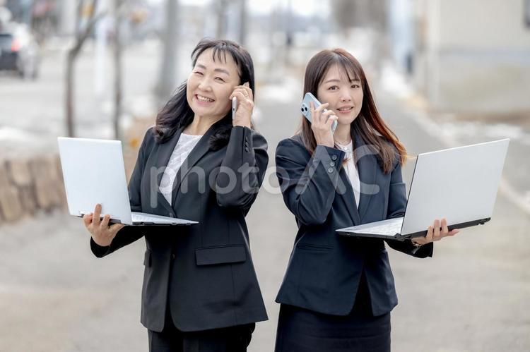 スマホとPCを持った二人の女性 ビジネス,笑顔,チームの写真素材