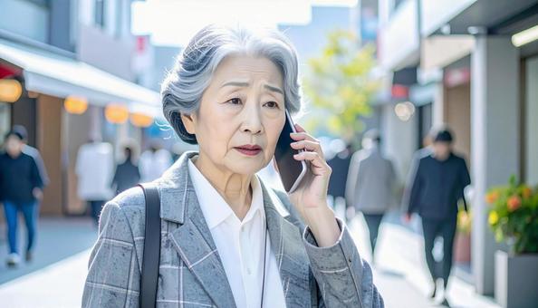 困った表情で電話する高齢者の写真