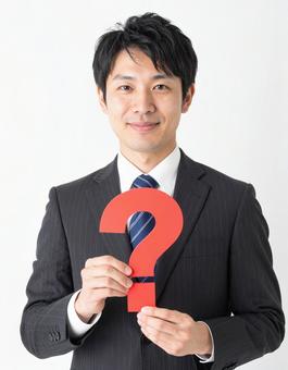 クエスチョンマークのオブジェを持つ男性 クエスチョンマークのオブジェを持つ男性の写真