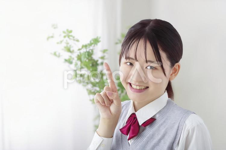 笑顔で指差しポーズをする女子高生 指差し,ワンポイント,アドバイスの写真素材