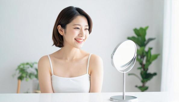 鏡で目元をチェックする女性 鏡で目元をチェックする女性の写真