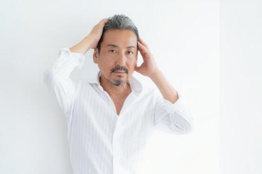 リビングでヘアケアをするミドルの男性 リビングでヘアケアをするミドルの男性 ヘアケア,育毛,ビューティーの写真素材