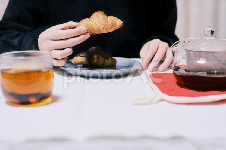 クロワッサンを食べようとする人 紅茶,ドリンク,温かいの写真素材