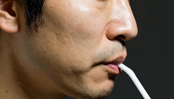 ストローで飲み物を飲むアジア人男性 ストローで飲み物を飲むアジア人男性の写真