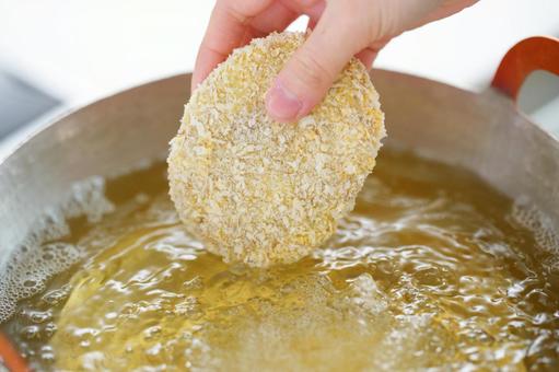 コロッケを揚げようとしている人の手 コロッケを揚げようとしている人の手 コロッケ,料理,入れるの写真素材