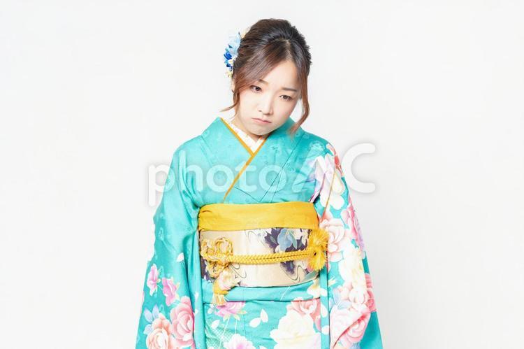 白背景の前に立って、落ち込んだポーズをする振袖を着た女性 女性,落ち込む,失敗の写真素材