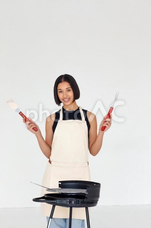 カメラ目線で両手に調理器具を持っている女性 女性,人物,エプロンの写真素材