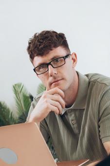 椅子に座って手に持ってノートパソコンを使っている筋肉質な男性 男性,外国人,欧米人の写真素材