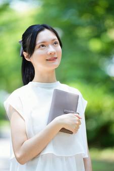 白いノースリーブワンピースの女性が本を片手に持つの写真