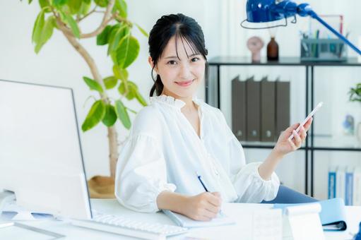 オフィスでスマホを持つビジネスウーマン スマホ,笑顔,ビジネスウーマンの写真素材