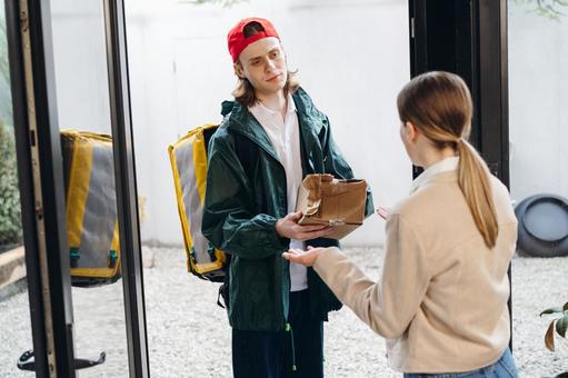 玄関で潰れた段ボール箱を見せる配達員の男性 配達,フードデリバリー,デリバリーの写真素材